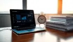 Escritorio moderno con laptop y reloj mecánico junto a reportes financieros, simbolizando tecnología y trabajo tradicional.
